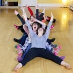 Vibrant children doing yoga in a fun, teamwork activity indoors for holistic health and wellbeing.