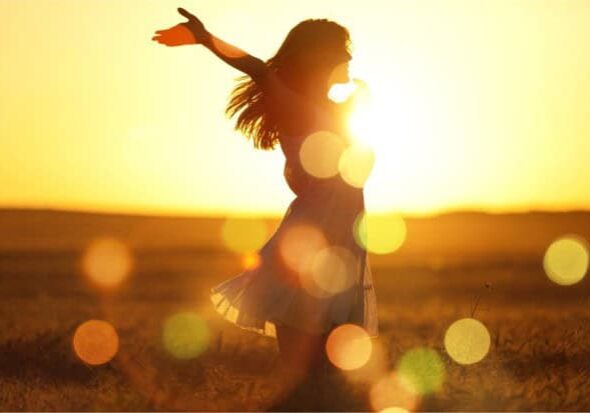 Silhouette of a woman dancing at sunset, bright light, outdoor, free, joyful, vibrant, summer, warm, carefree, happiness, lighting the way.