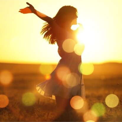 Silhouette of a woman enjoying sunset with warm lighting, symbolising hope and guidance from Lighting the Way.