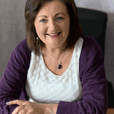 Bright smiling woman at desk with colourful nails, representing Lighting the Way opticians.